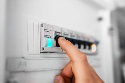 Male hand switching on fuse board.