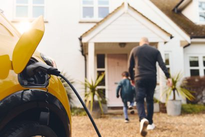 Electric car charging on driveway outside home with family